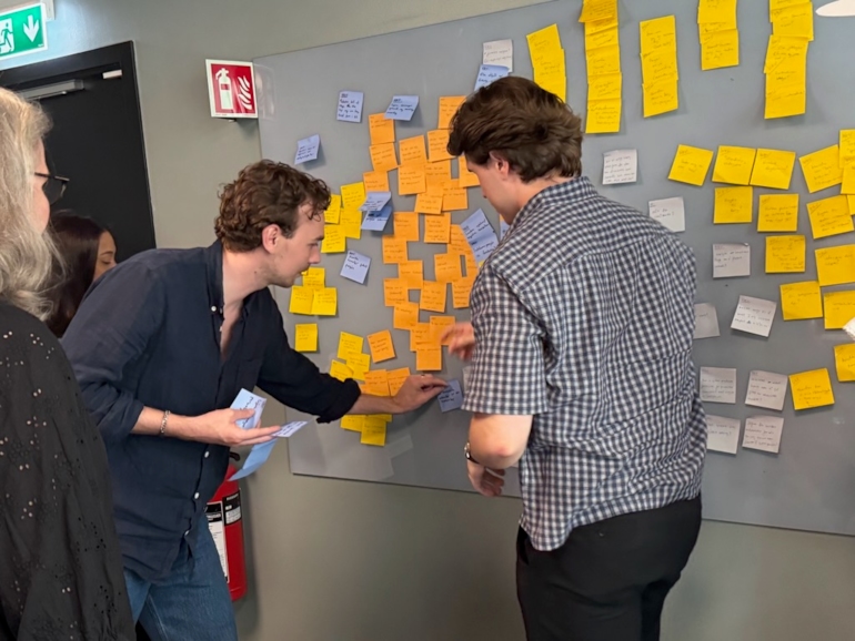 To gutter som monterer postit-lapper. Foto. 